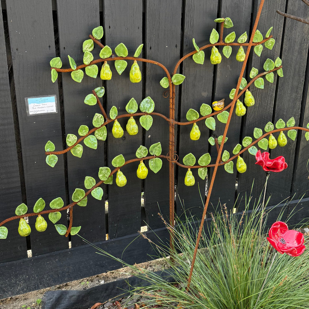 Garden scene with a ceramic espaliered pear tree against a wall.
