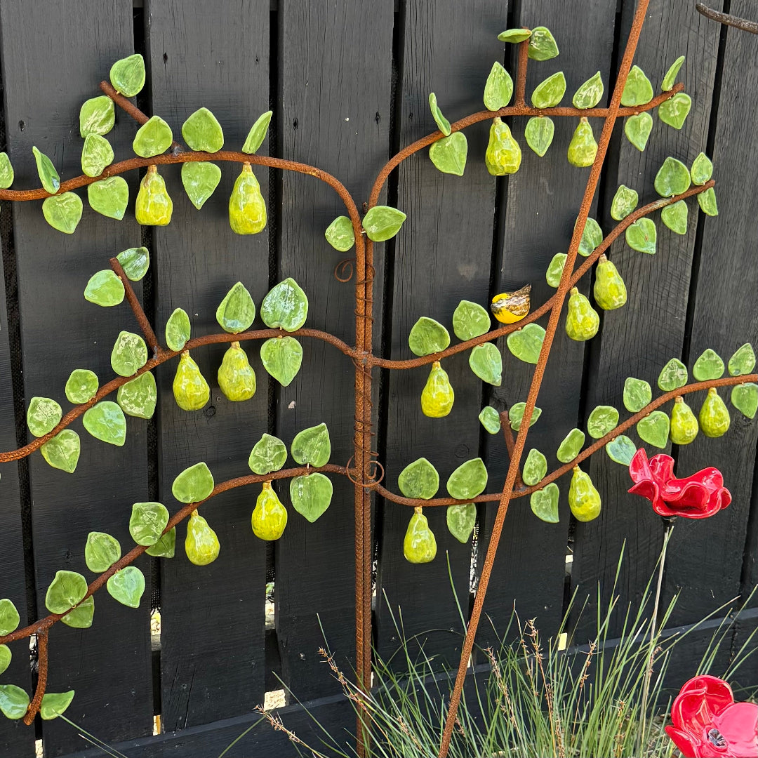 Garden scene with a ceramic espaliered pear tree against a wall.