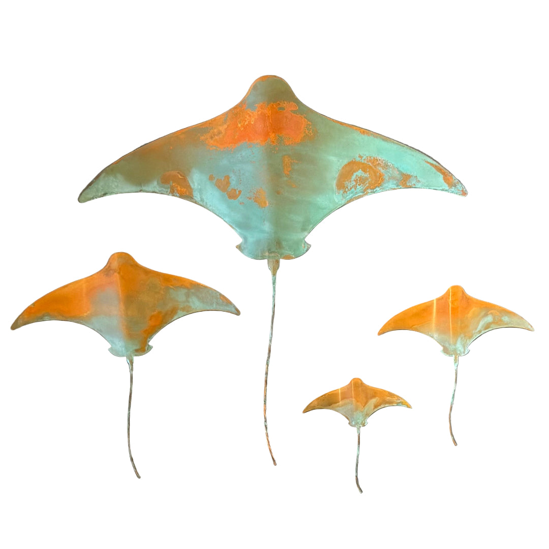 Four stingrays with an orange and green patina on a white background