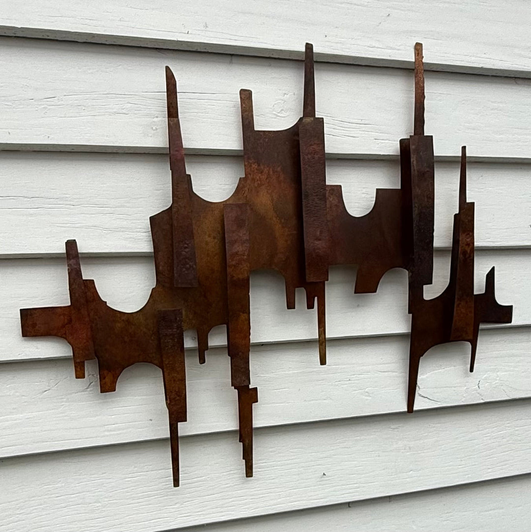 Copper metal wall sculpture on a white weatherboard background