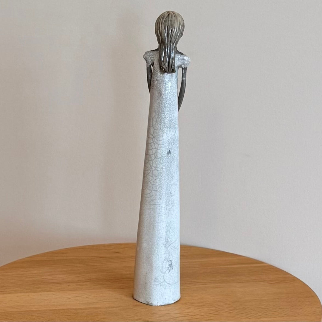 Back view of a ceramic figure on a wooden surface