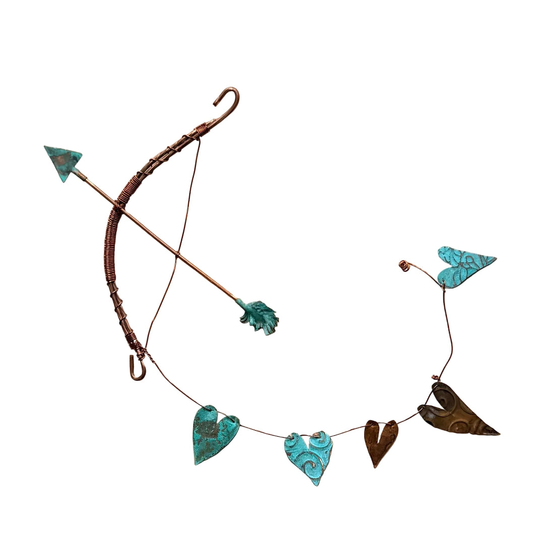 Wall hung copper bow & arrow trailing turquoise & copper hearts on a white wall