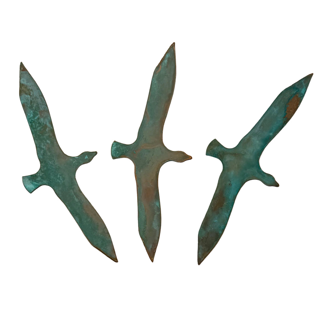 Three copper birds on a white wall