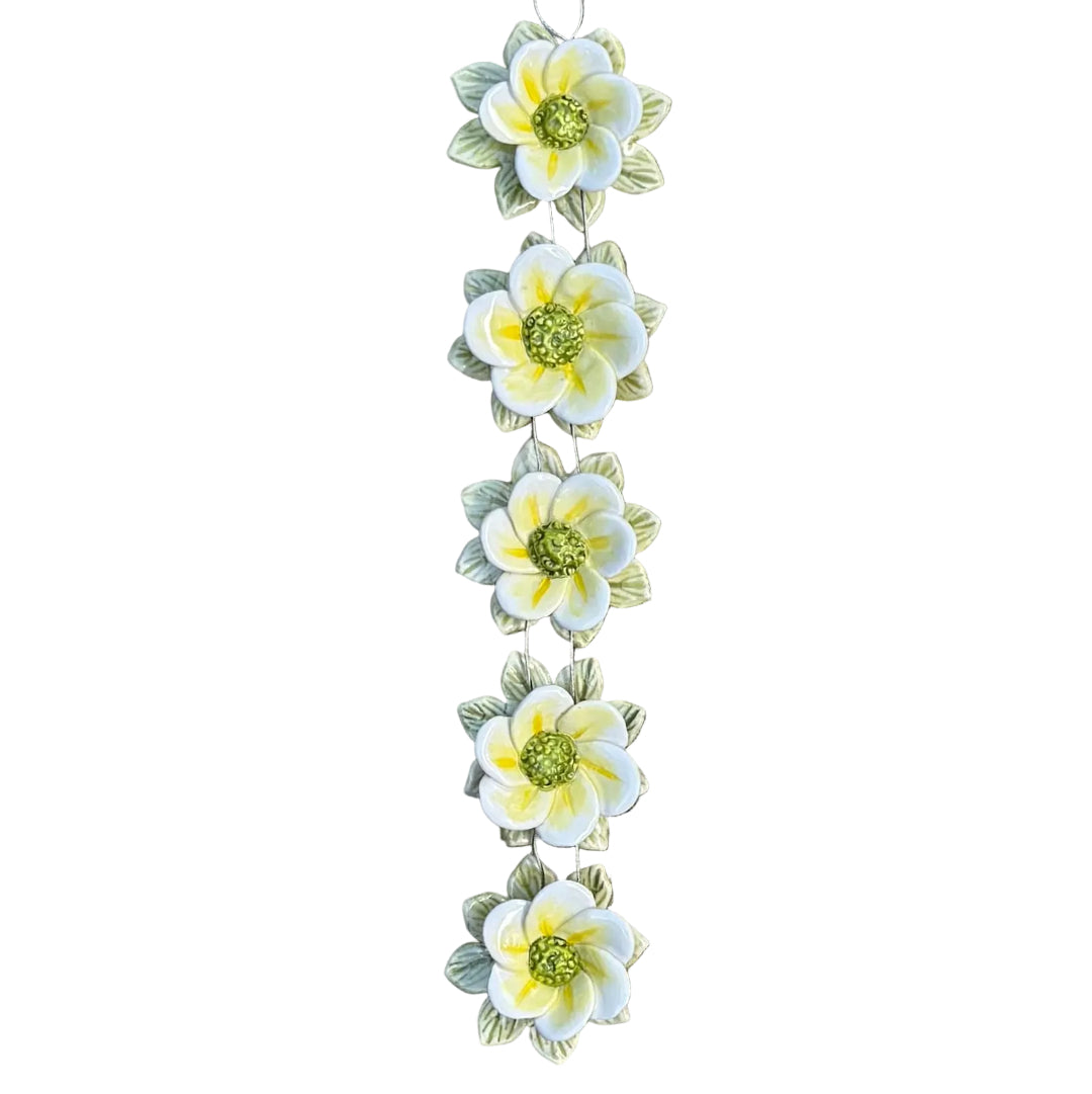 Decorative floral wall hanging with 5 yellow, white and green ceramic flowers on a white surface