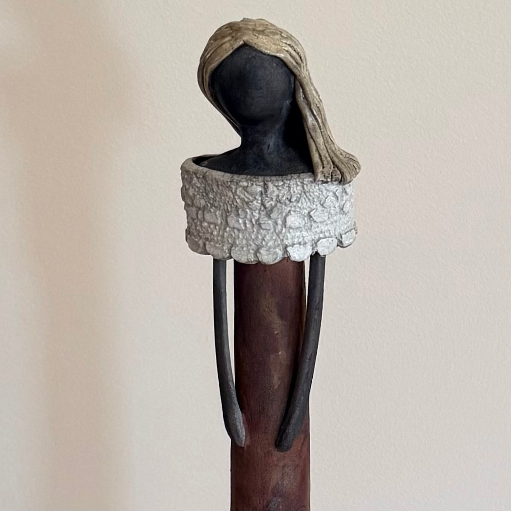 Close up view of a ceramic figure against a plain background