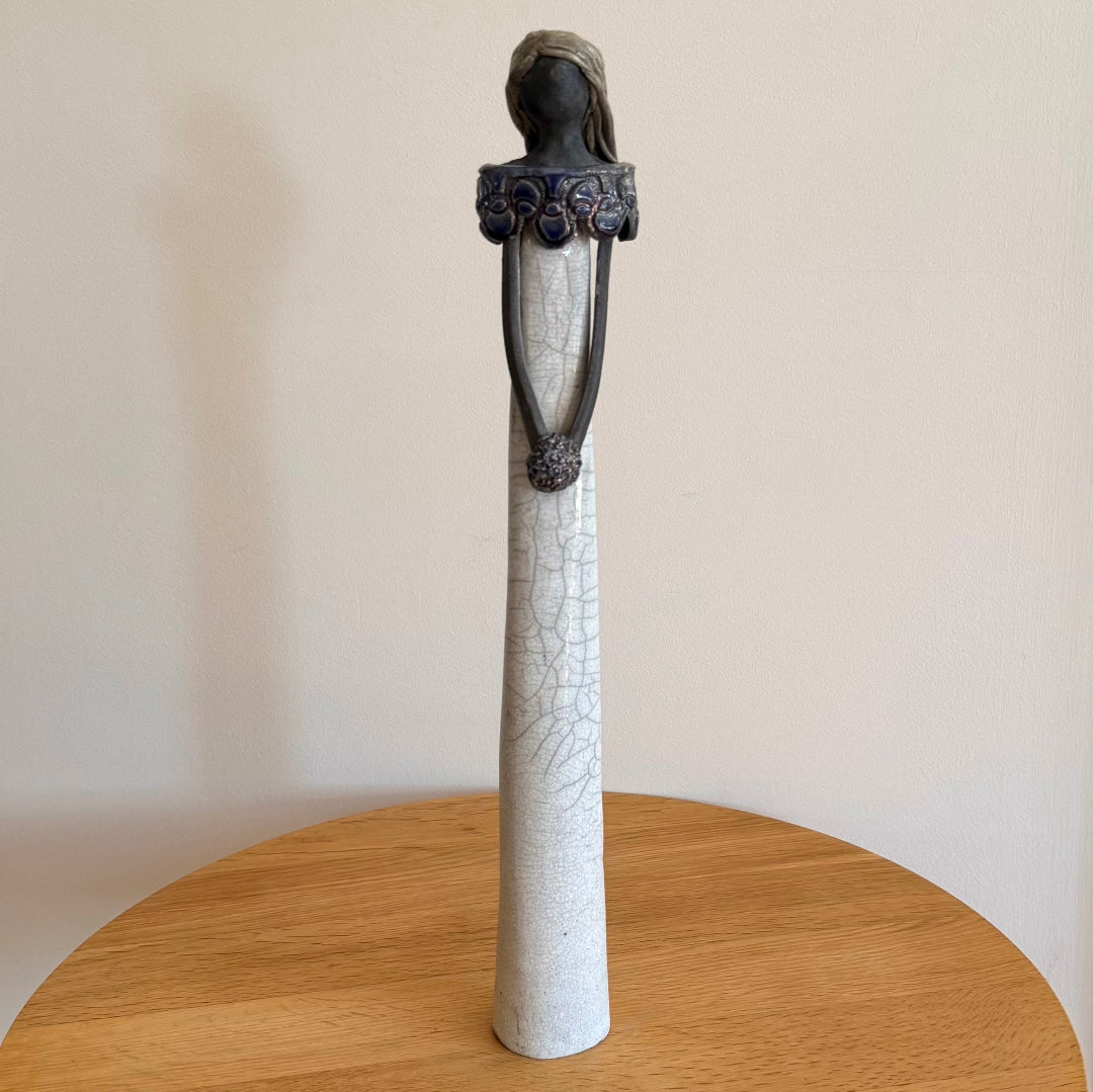 Ceramic figure of a lady with ornate collar & posy on a wooden surface table