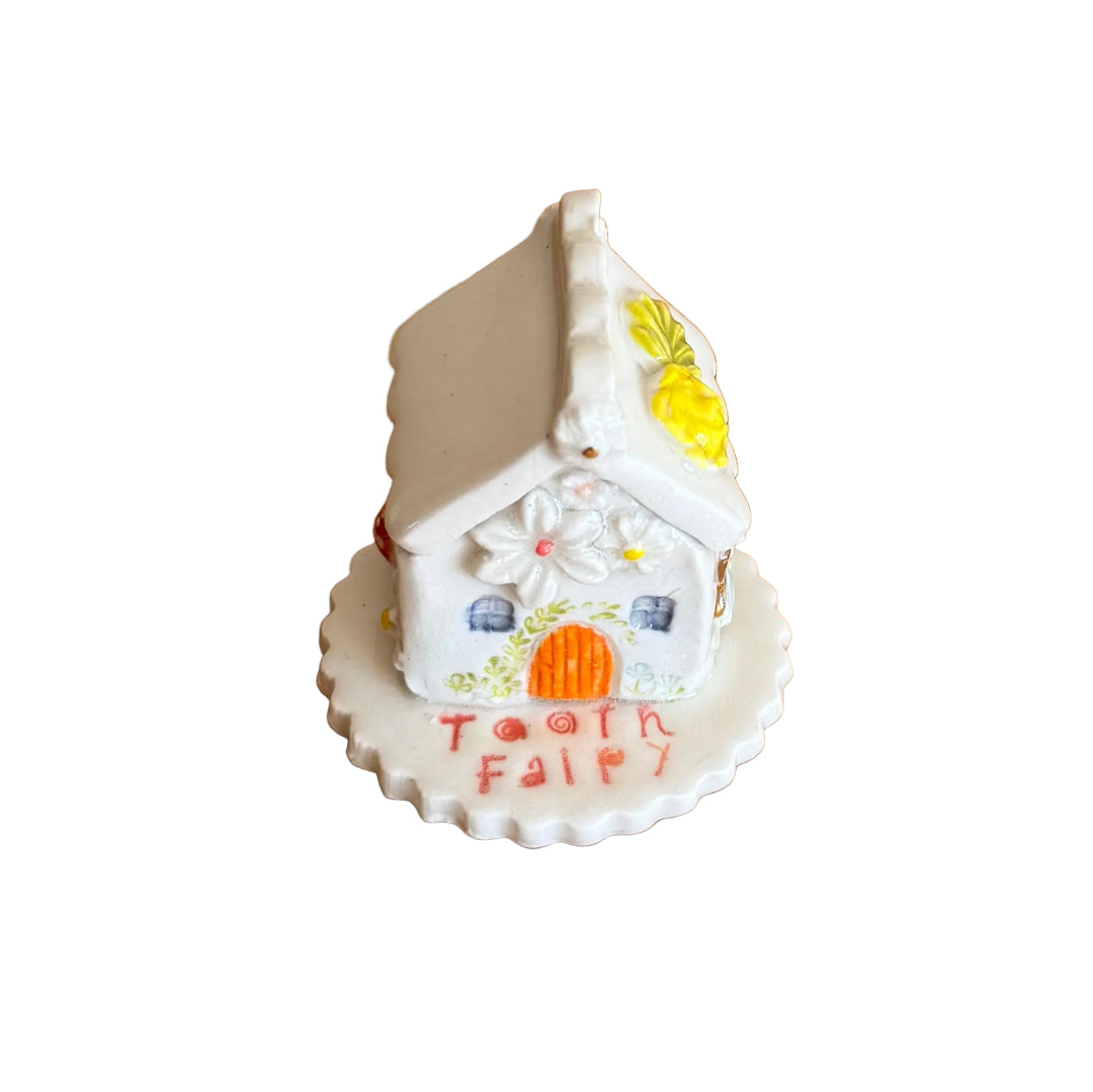 Decorative ceramic trinket box small house with 'Tooth Fairy' text on a white surface