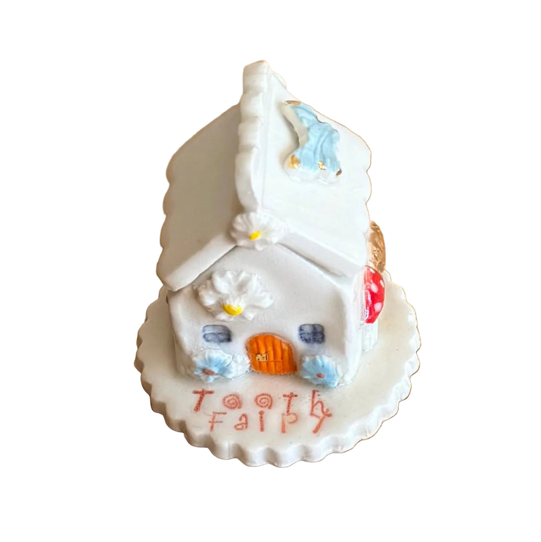 Decorative ceramic trinket box small house with 'Tooth Fairy' text on a white surface