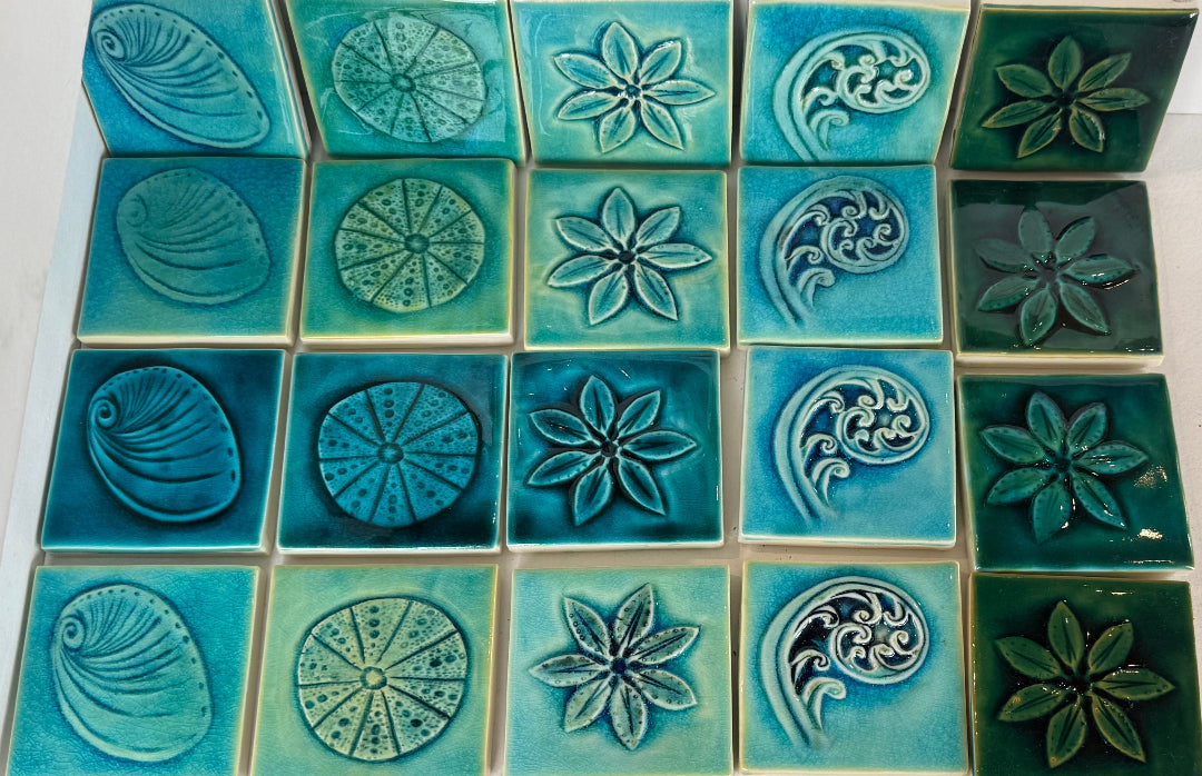 Collection of decorative tiles with floral and shell patterns in shades of blue and green.