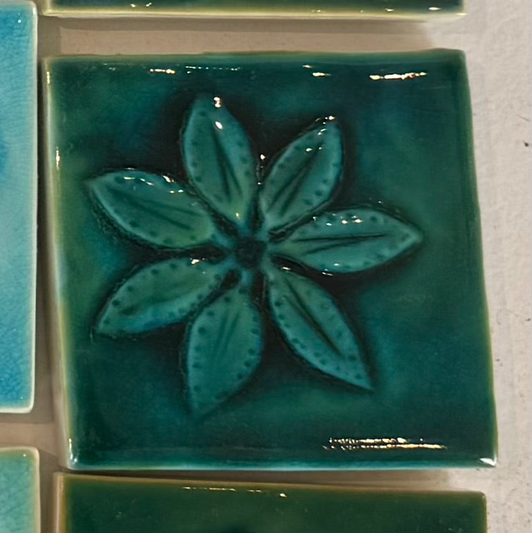 Green ceramic tile with a floral design on a white background