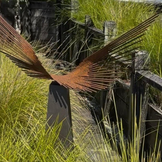 Decorative metal sculpture with rusted finish in a grassy outdoor setting