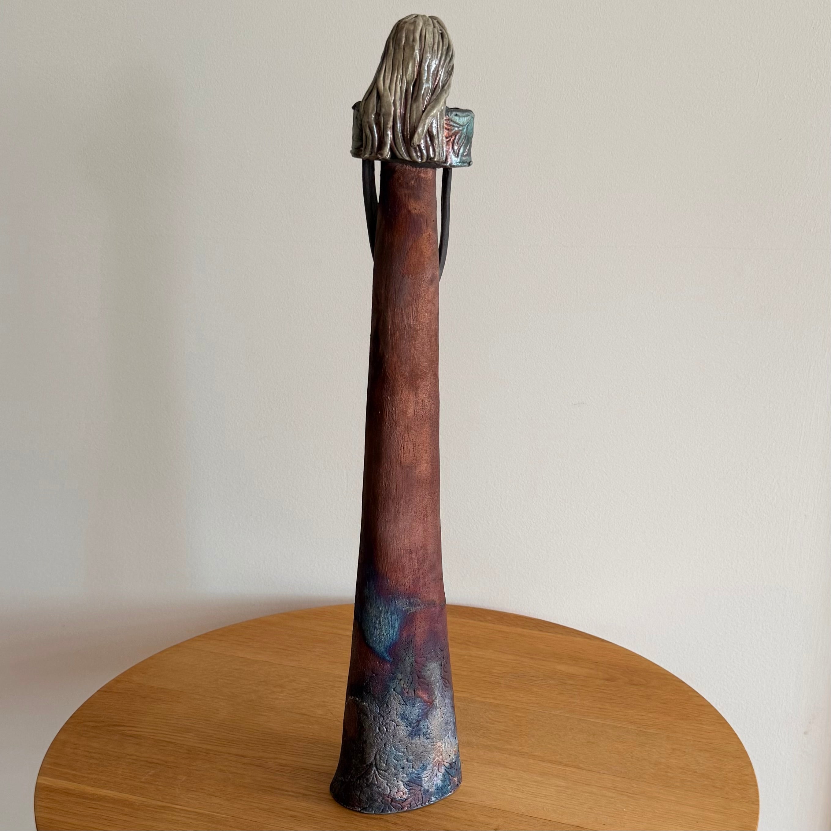 Back view of a ceramic woman on a wooden surface