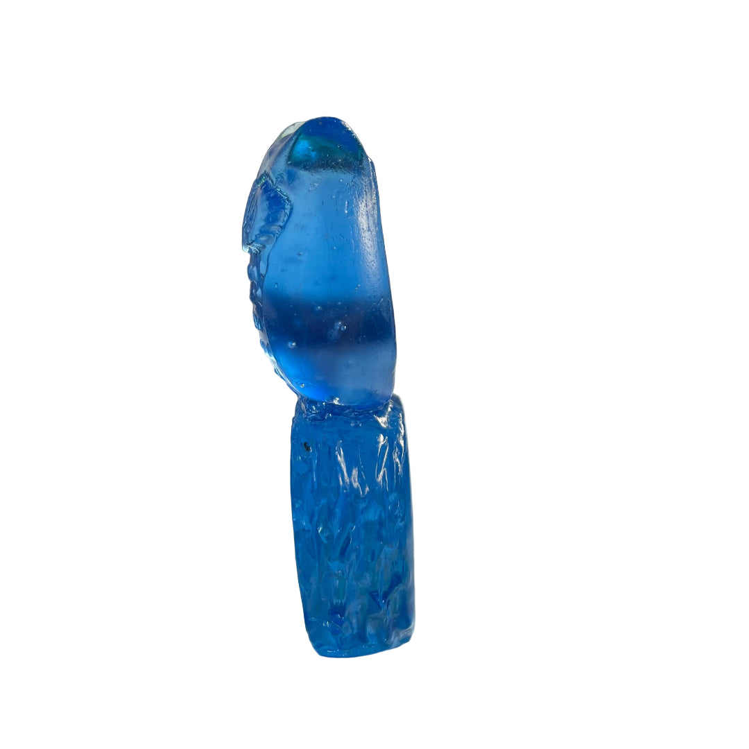 Side view of a blue glass owl sculpture on a white surface