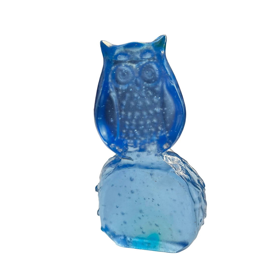 Back view of a blue glass owl sculpture on a white surface