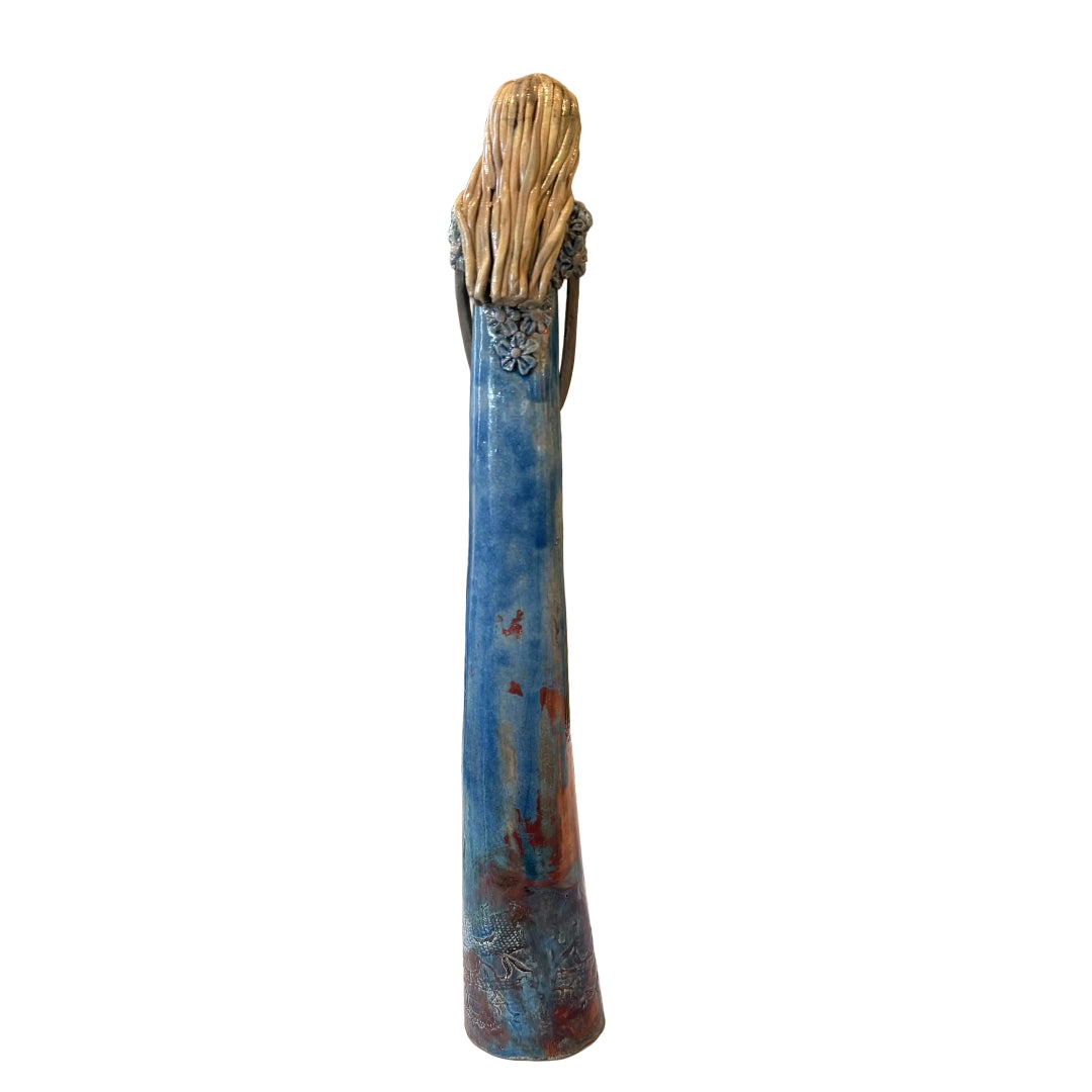 A tall, narrow ceramic sculpture with a textured, tree-like top and a glazed blue body with rust-colored accents.