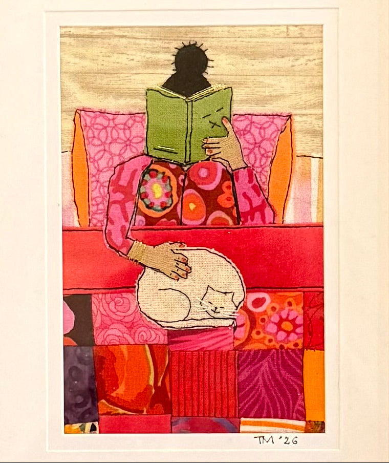 Handstitched artwork of a woman reading a book with a cat on her lap