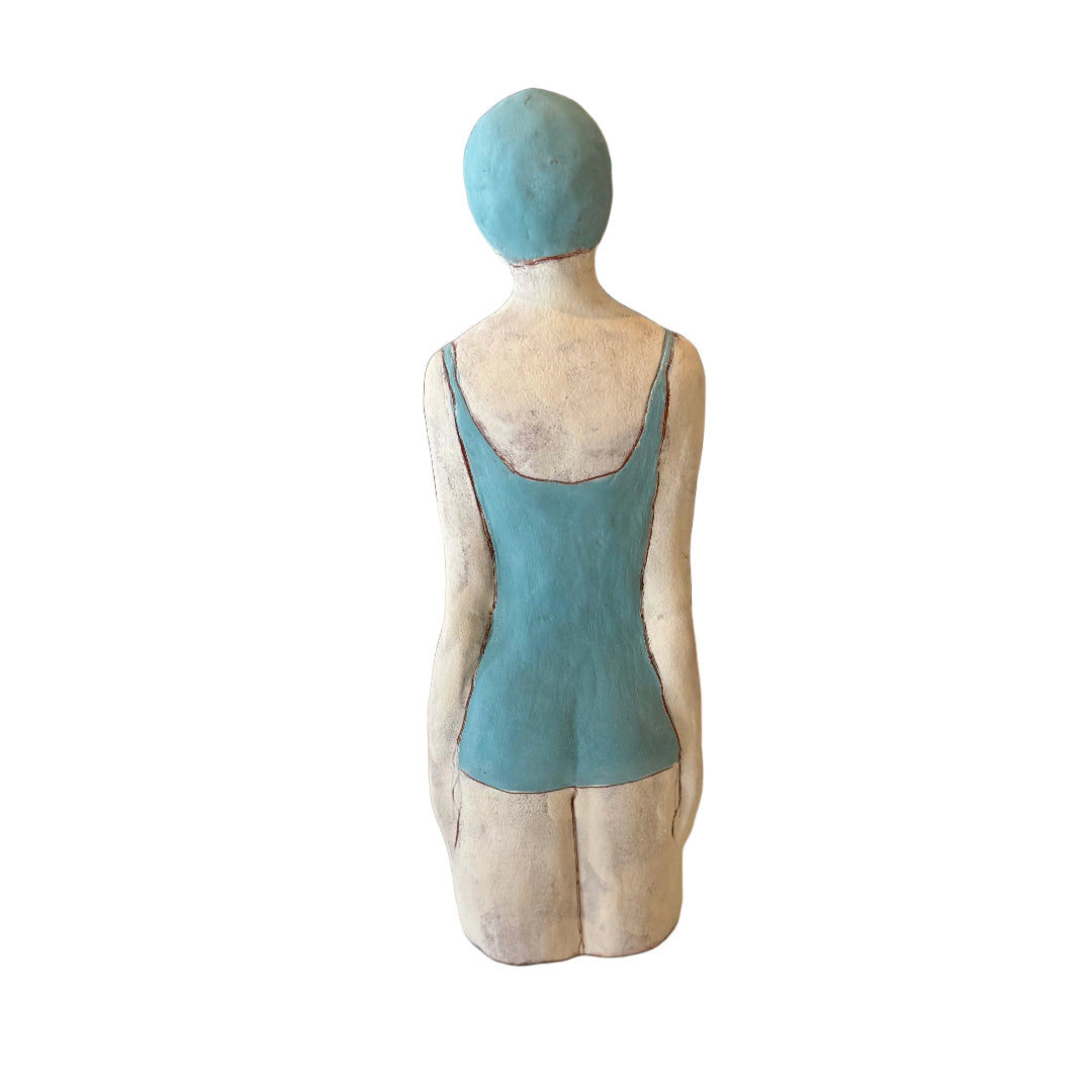 Back view of a statue of a woman in a blue swimsuit against a white background.