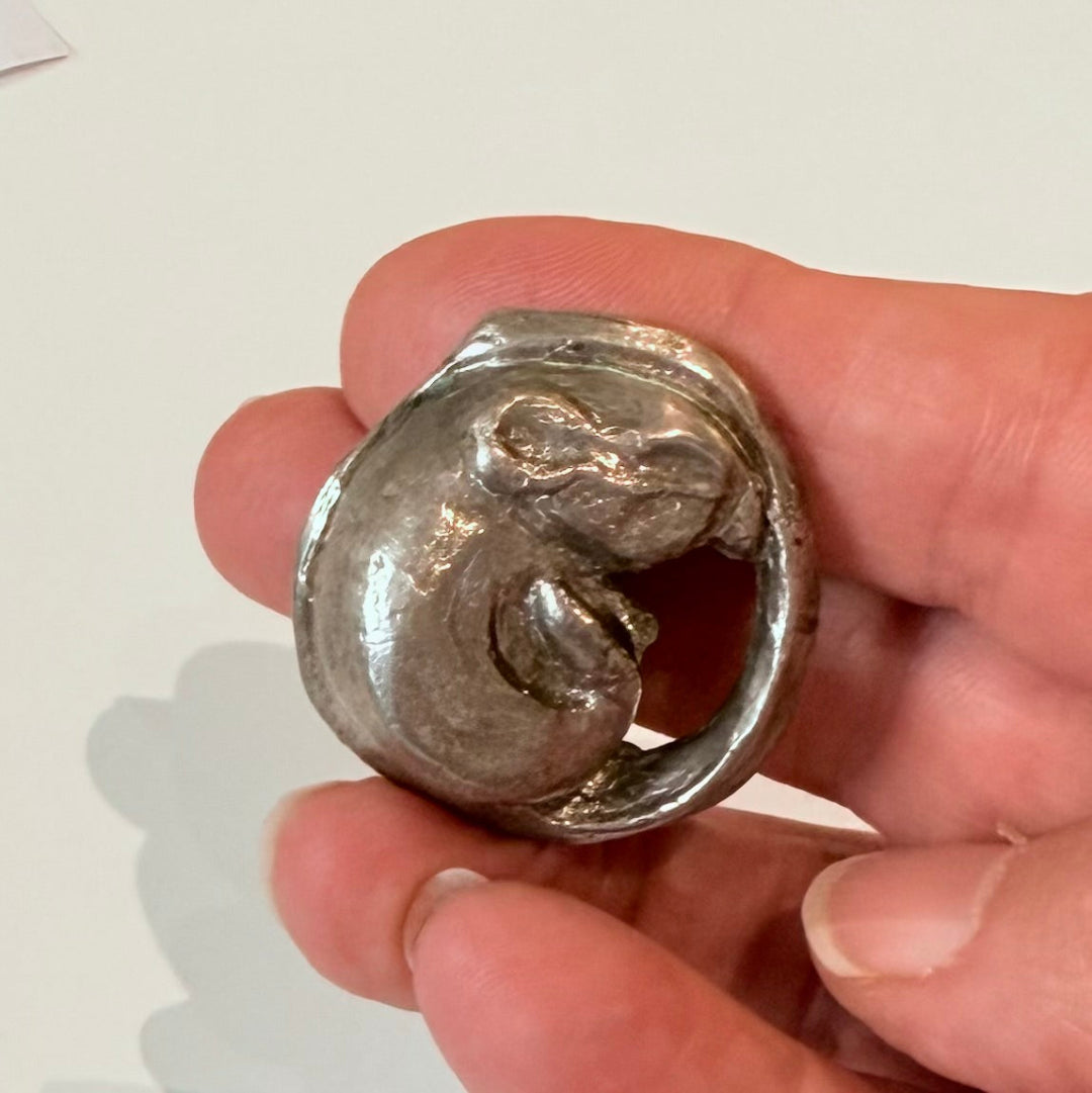 Hand held silver plated cast bronze miniature mouse curled up on a white background