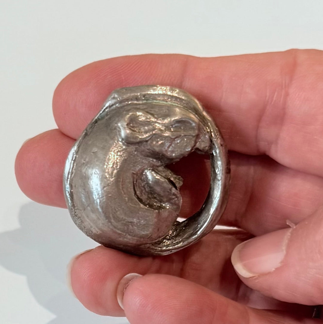 Hand held silver plated cast bronze miniature mouse curled up on a white background