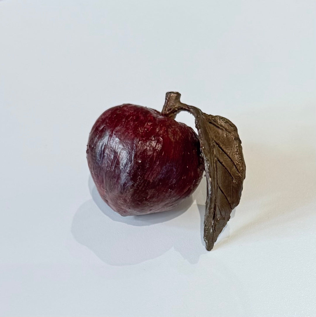 Painted bronze miniature peach with a leaf on a white background