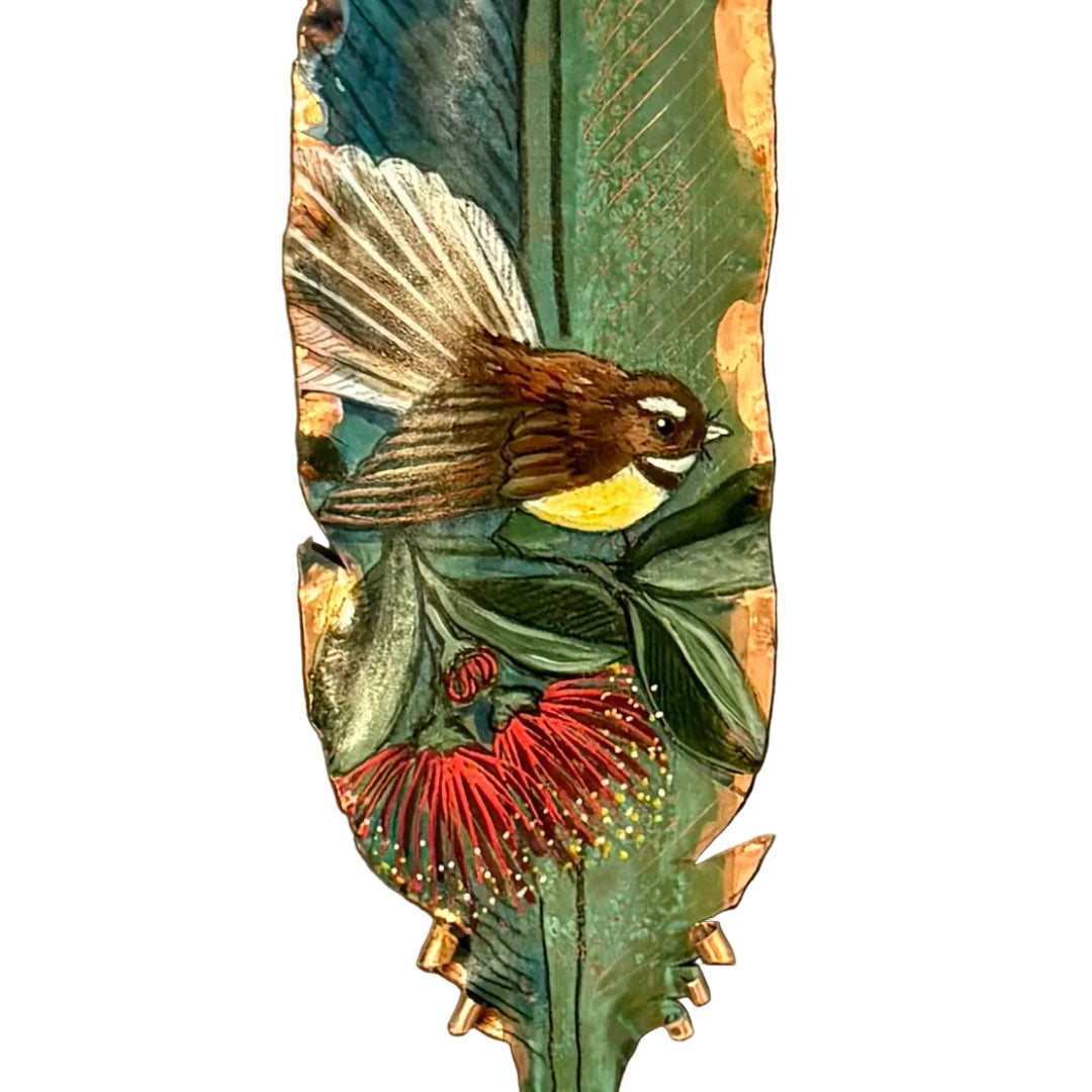 Close up of a painted  copper feather with a fantail bird and pohutakawa flower  on a white background