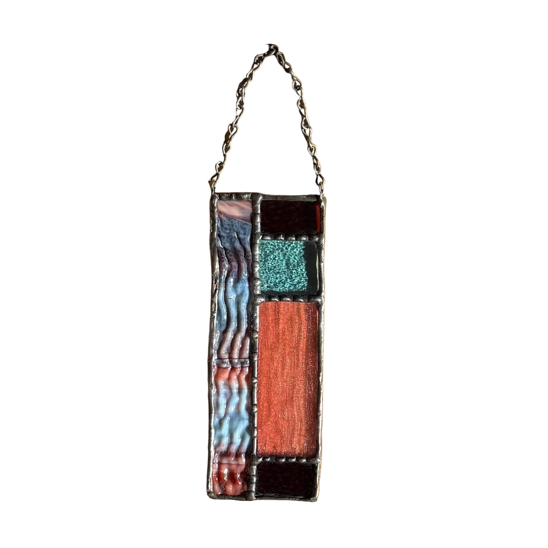 Decorative stained glass wall hanging with geometric design on a white wall