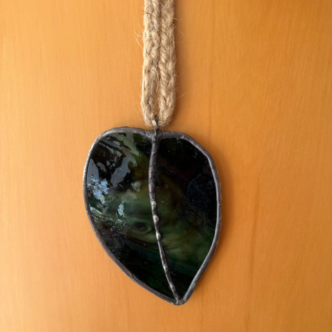 Glass Kawakawa Leaf wall hanging against a wood background