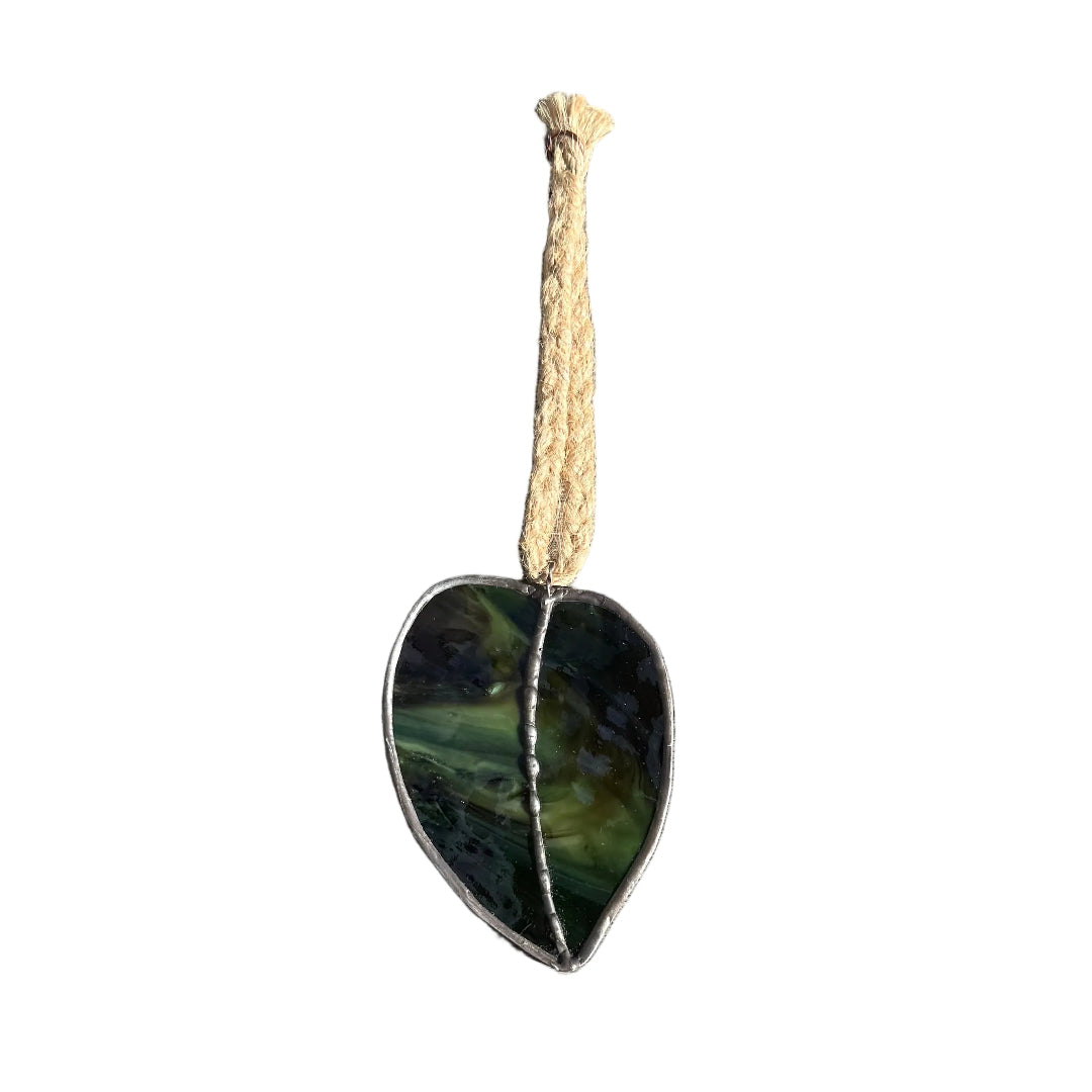 Glass dark green kawakawa leaf on a rope wall sculpture with a white background 