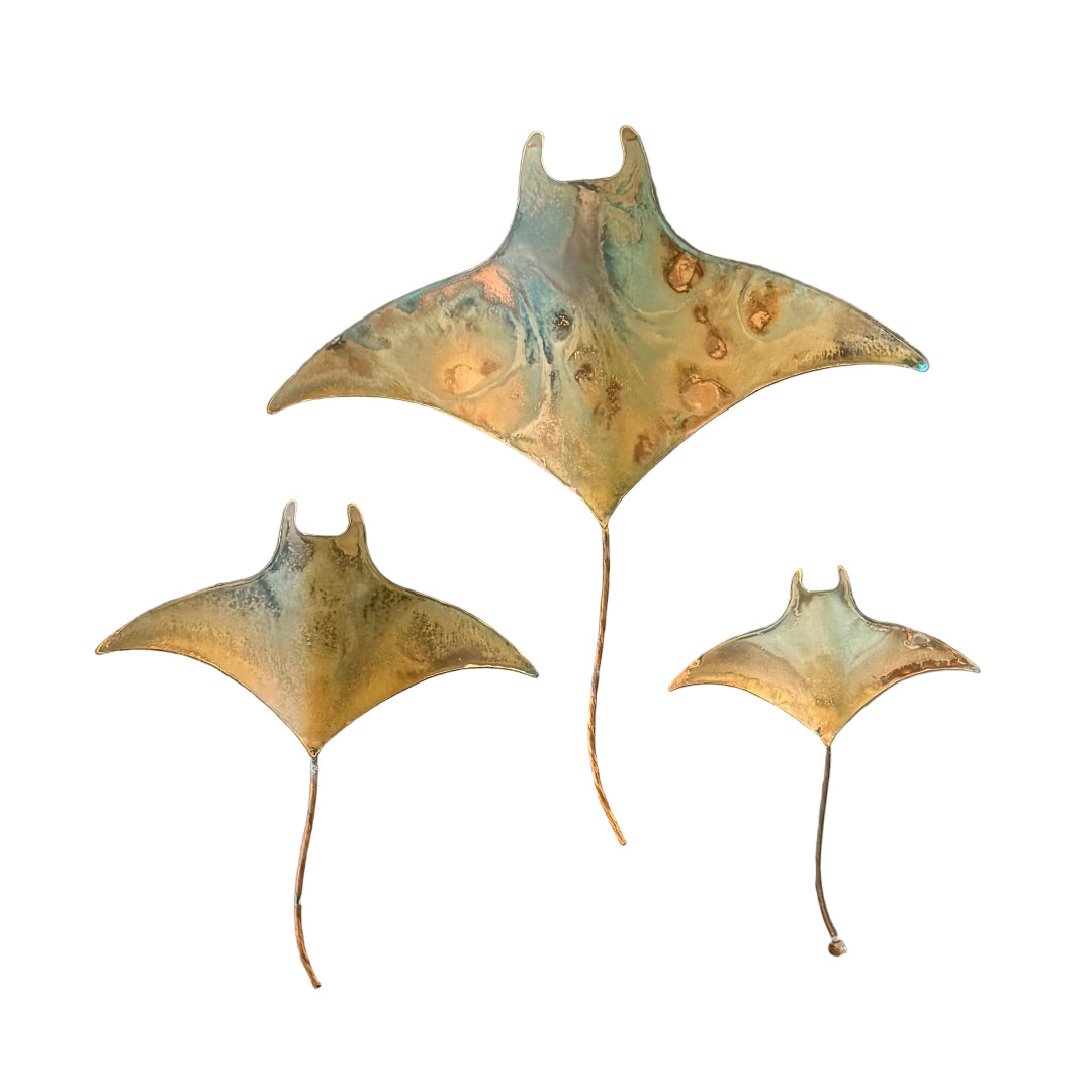 Three copper manta ray wall sculptures on a white background