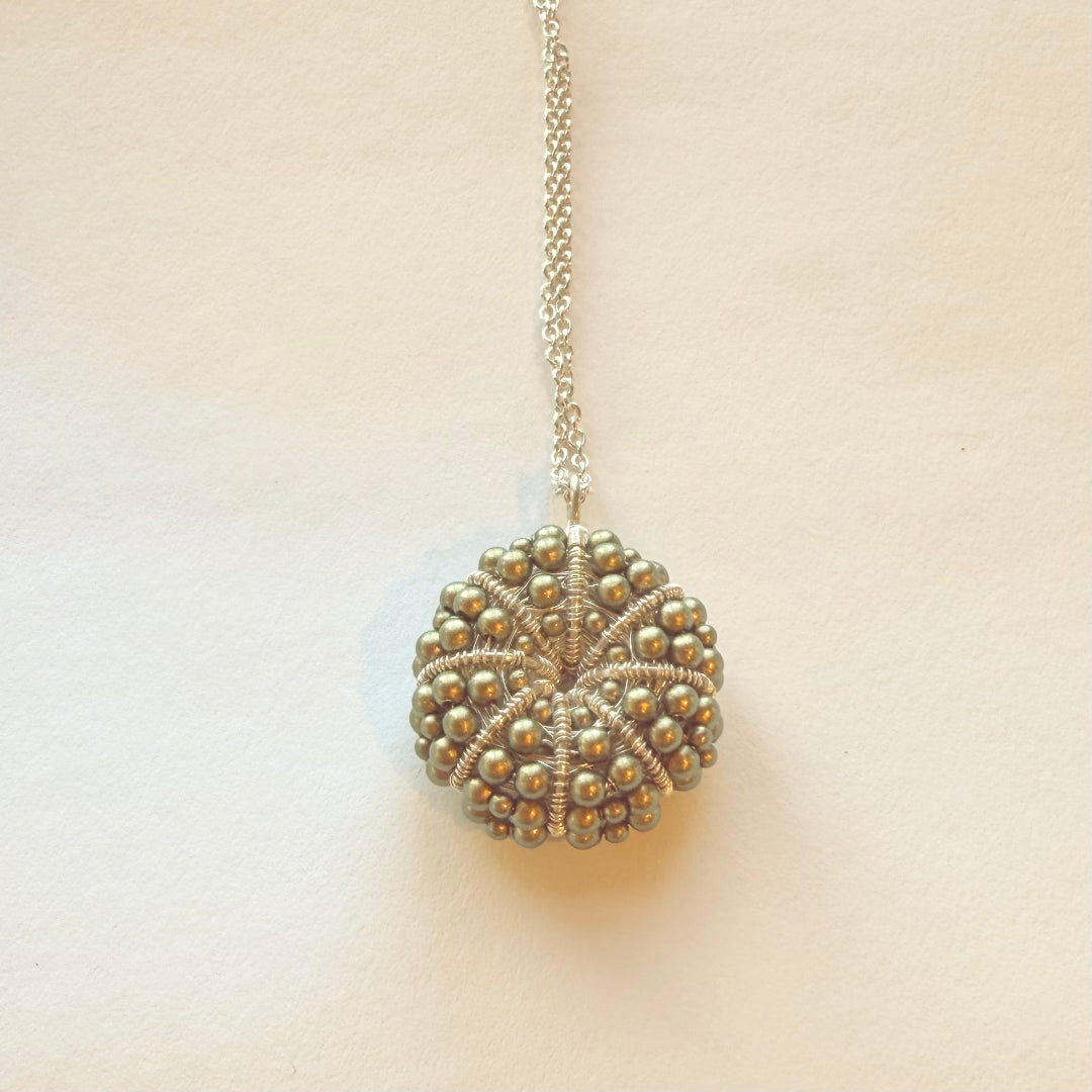 Necklace with a textured spherical pendant on a beige background