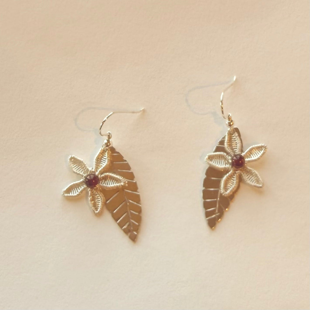 Pair of silver floral earrings on a beige background
