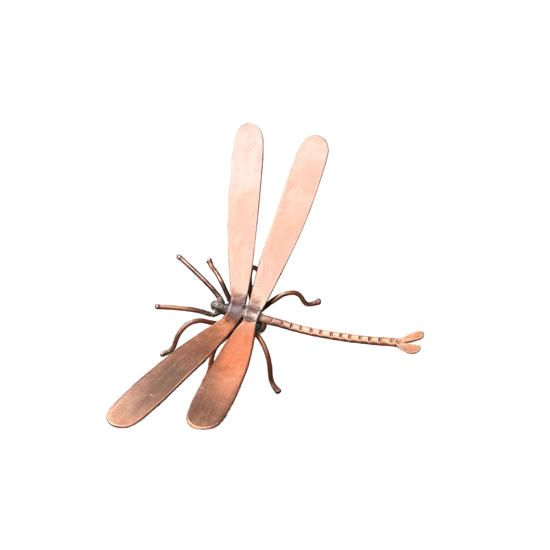 Copper dragonfly sculpture on a white surface
