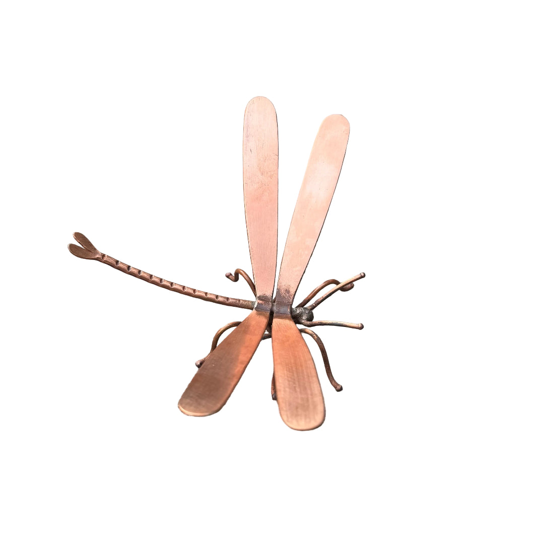 Copper dragonfly sculpture on a white surface
