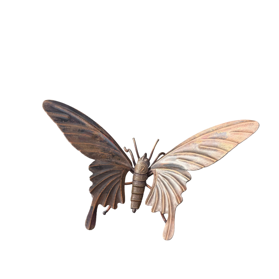 Copper butterfly sculpture with coin body on a white surface
