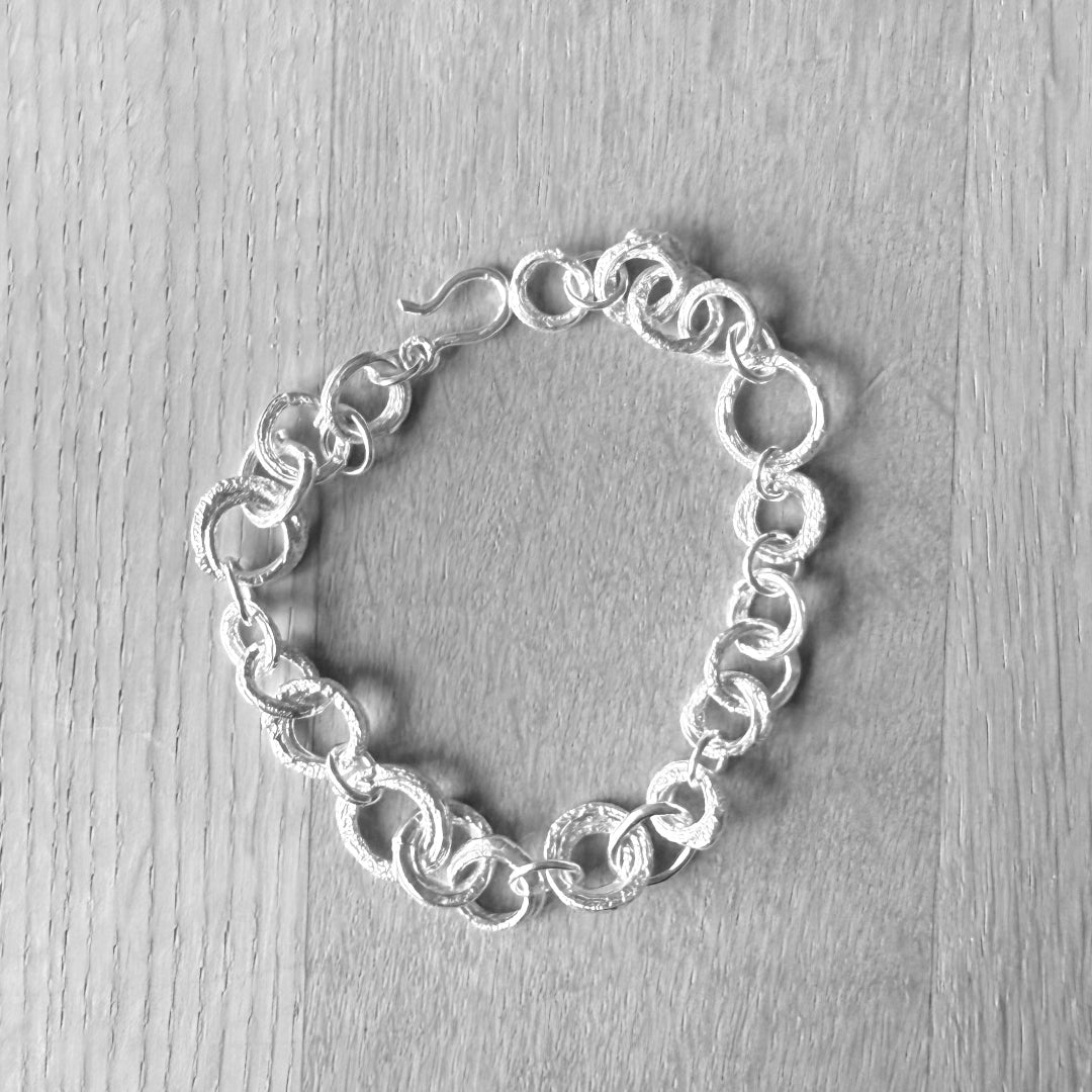 Silver chain bracelet on a light wooden surface