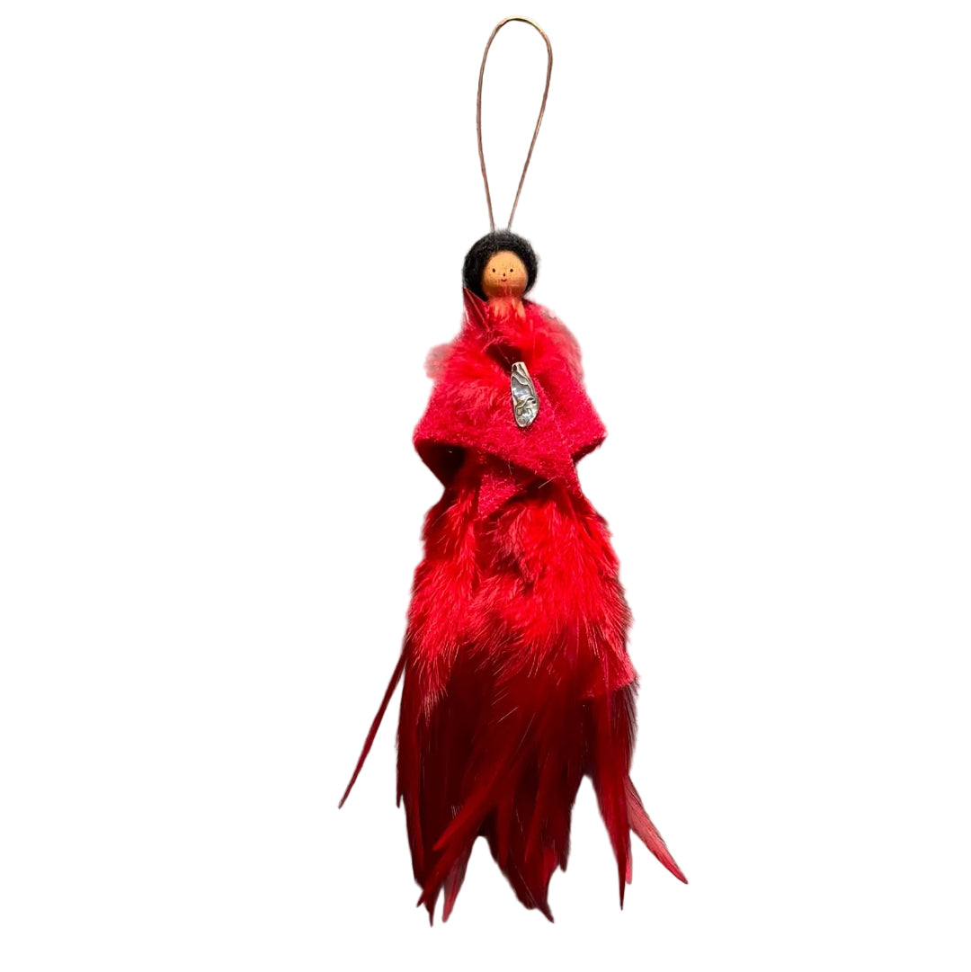 A handmade decorative hanging ornament featuring a small peg doll figure with black hair and a face, dressed in a red felt shawl with a paua shell & feather brooch , and a fluffy red feather skirt, suspended against a white background.