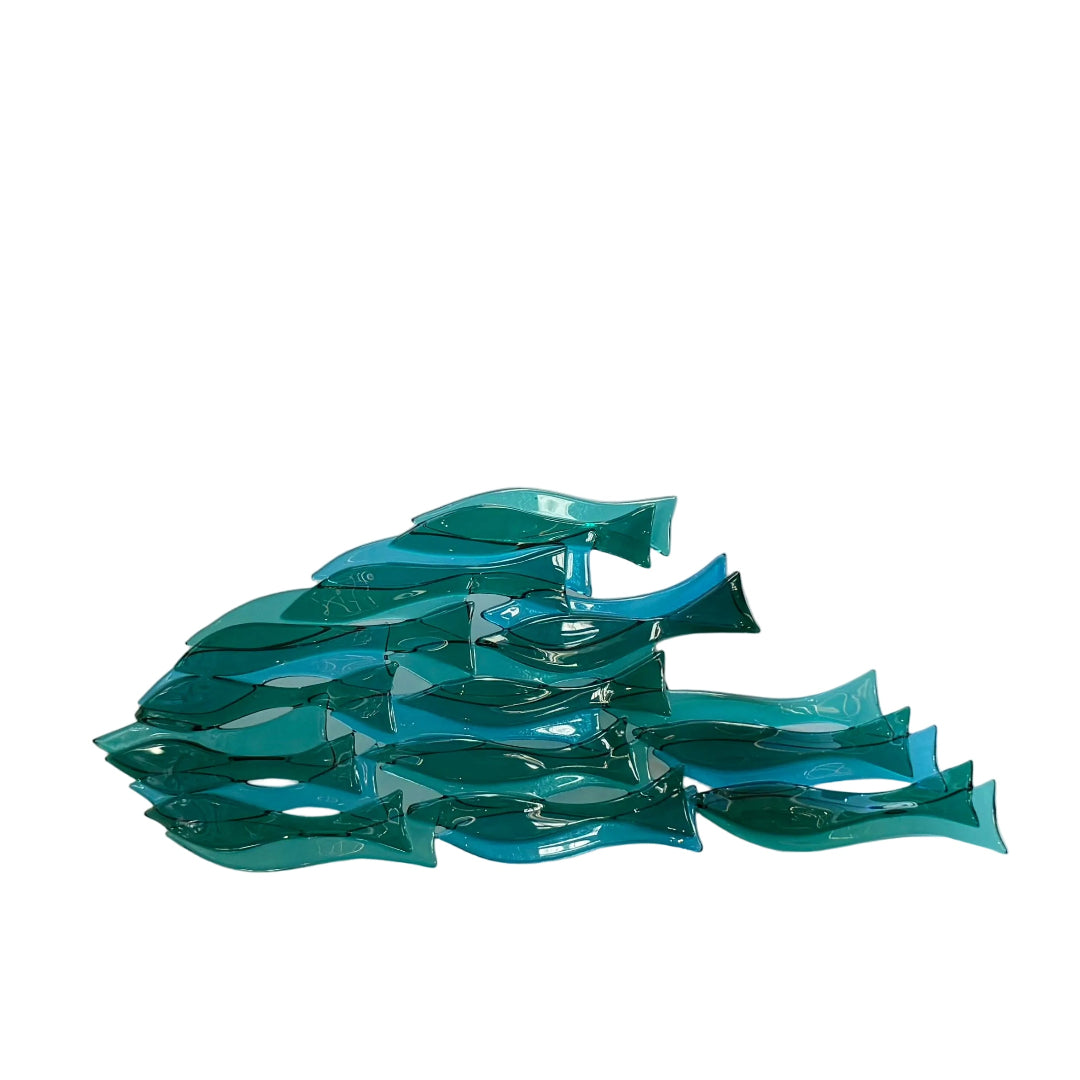 A translucent teal glass fish sculpture arranged on a white table. 