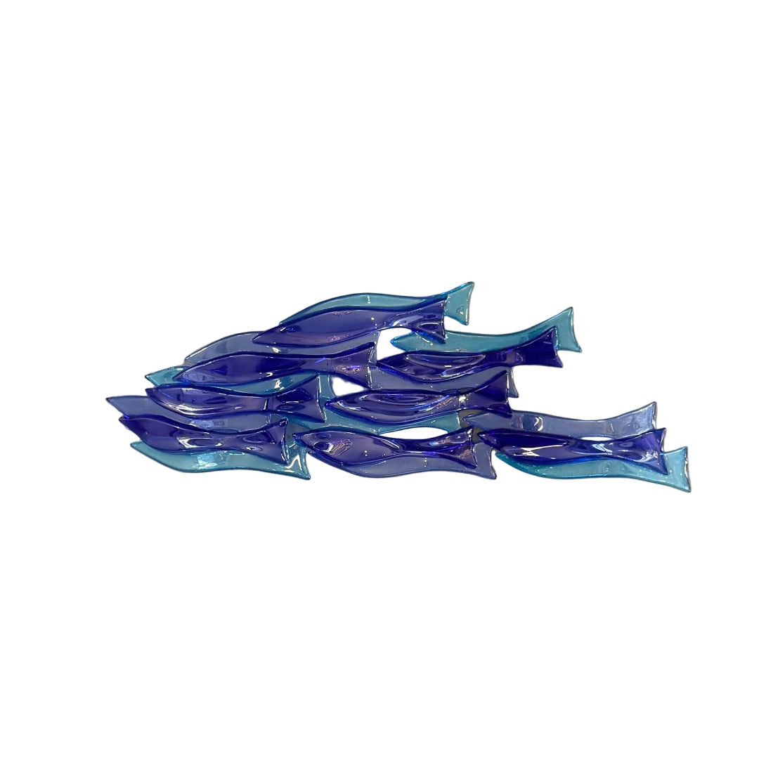 A translucent blue and teal glass fish sculpture sitting on a white surface.