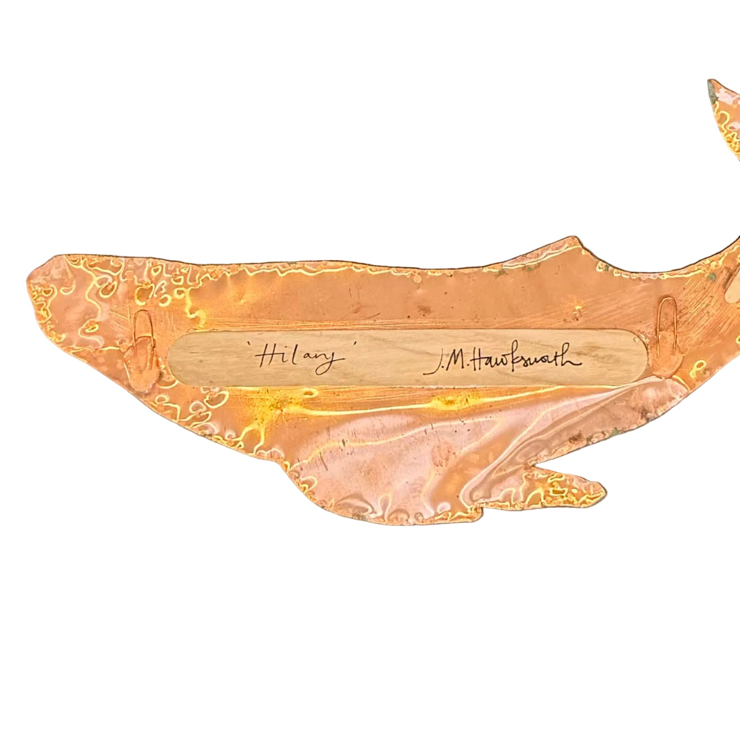 The back of a copper whale wall hanging with a central wooden inlay signed 'Hilary' and 'J.M. Hawksworth