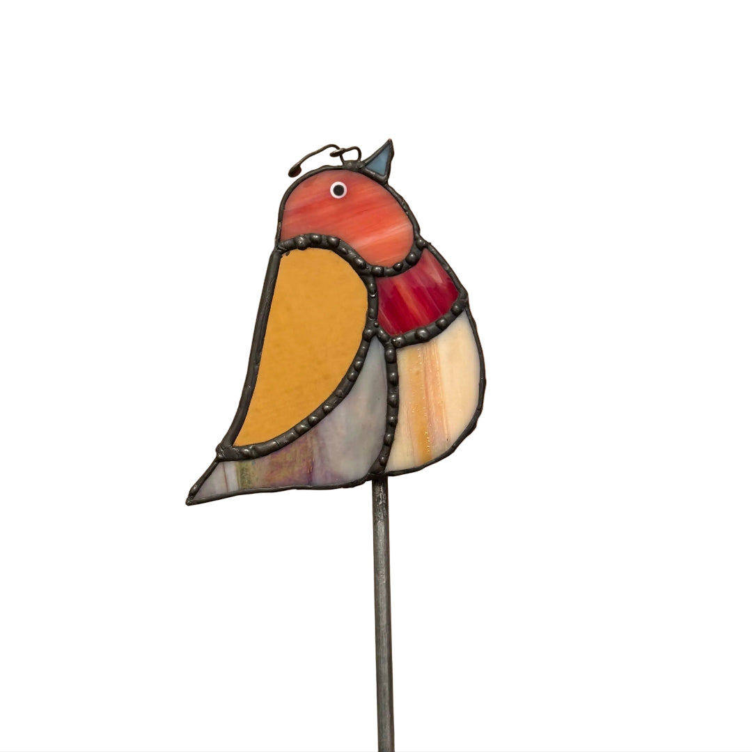 A stained glass bird garden stake featuring a robin design with red, yellow, and gray glass panels, set against a white carpeted floor.