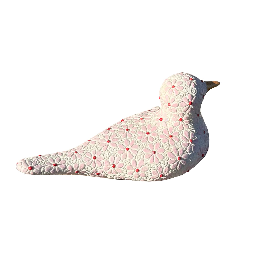 A decorative white ceramic bird figurine with a pink daisy flower pattern and a small gold beak, resting on white background.