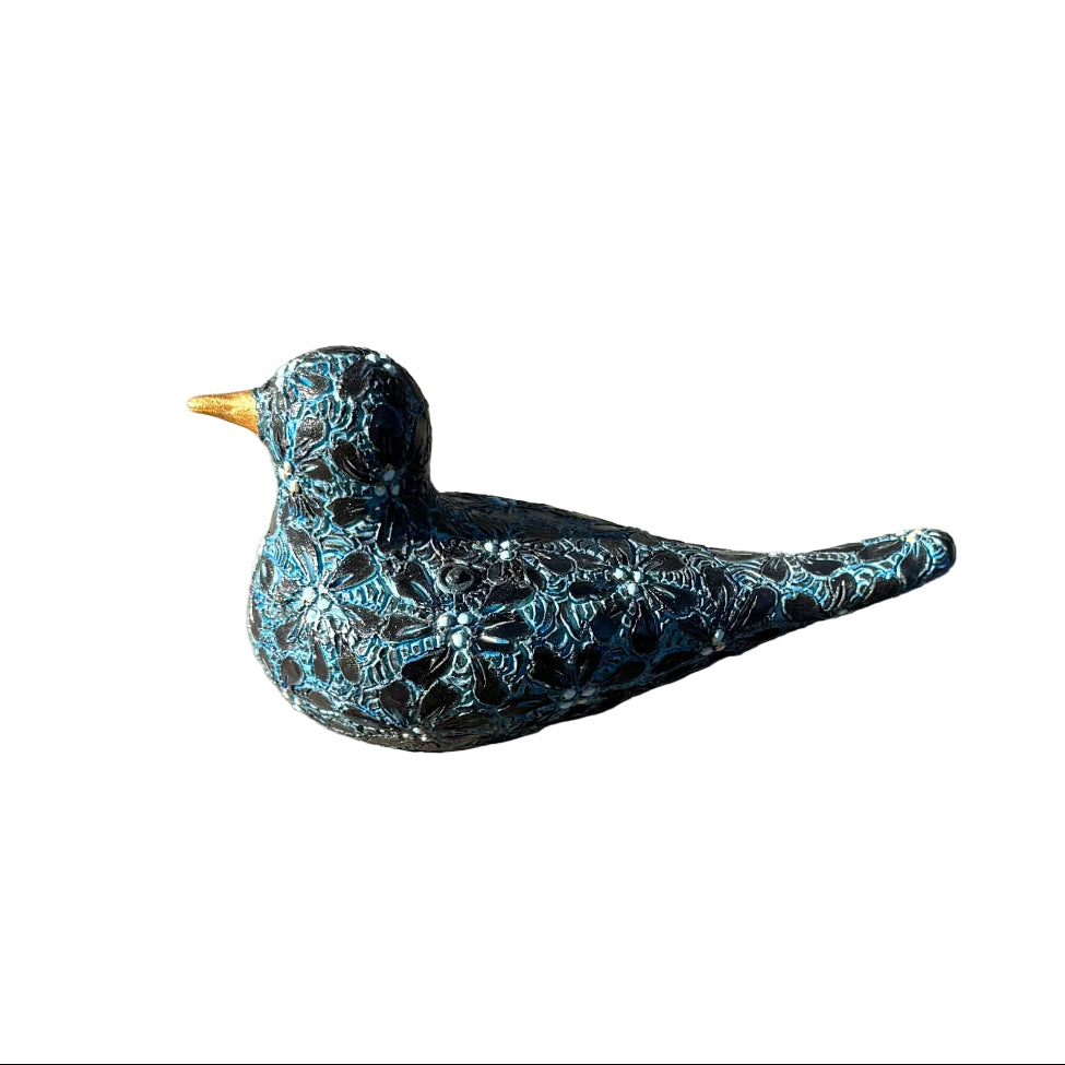 A decorative ceramic bird figurine with a black and turquoise flower pattern and a small gold beak, resting on white background.
