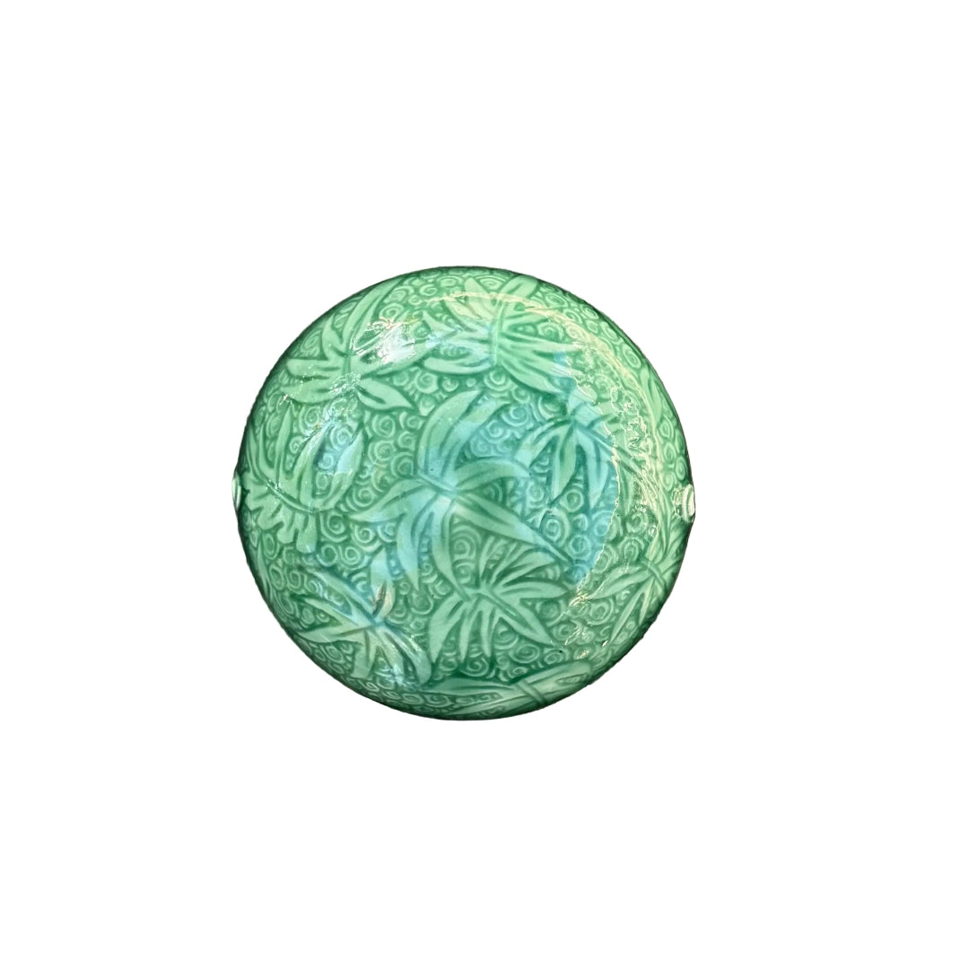 A round green ceramic trinket dish with embossed floral and leaf patterns, on a white background.