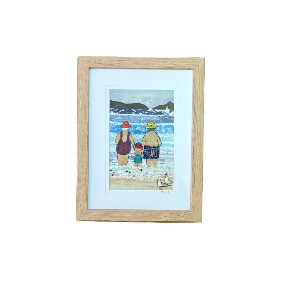 A small framed textile artwork with a colourful coastal depiction on a white background.