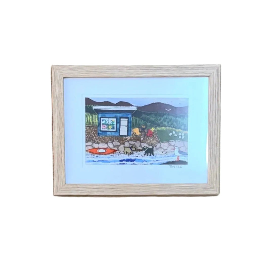 A small framed textile landscape artwork depicting a blue bach on a white background.