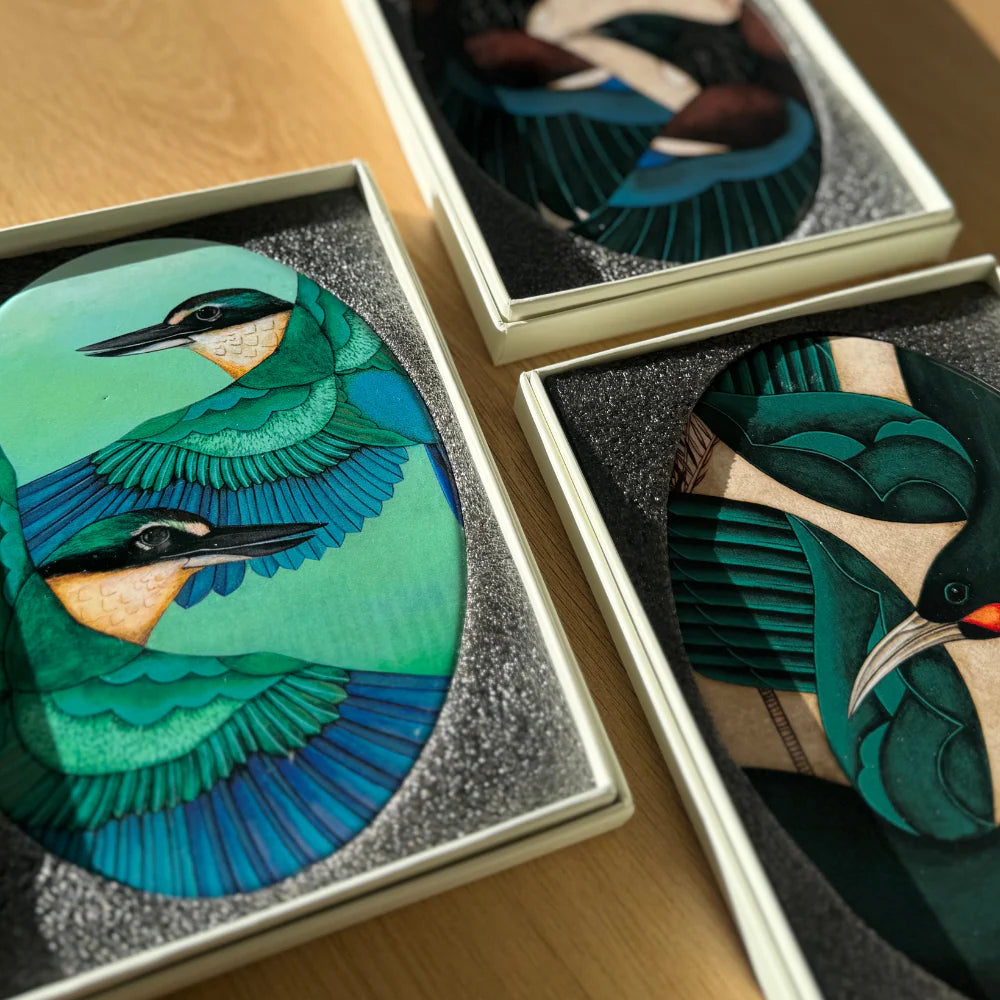 Three decorative items with bird designs on a wooden surface