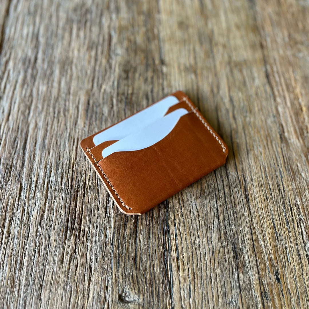 Brown leather cardholder with cards on a wooden surface