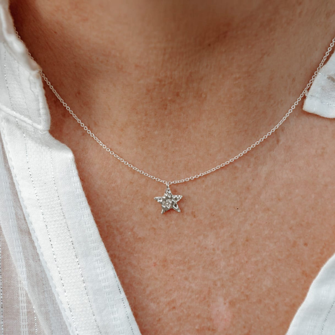 Star-shaped necklace on a person wearing a white shirt