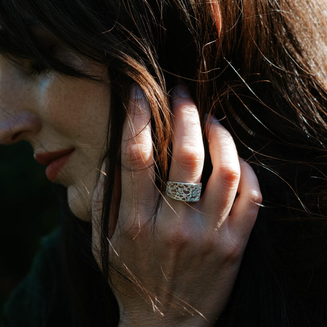 Person with a ring on their finger holding their head with dark background