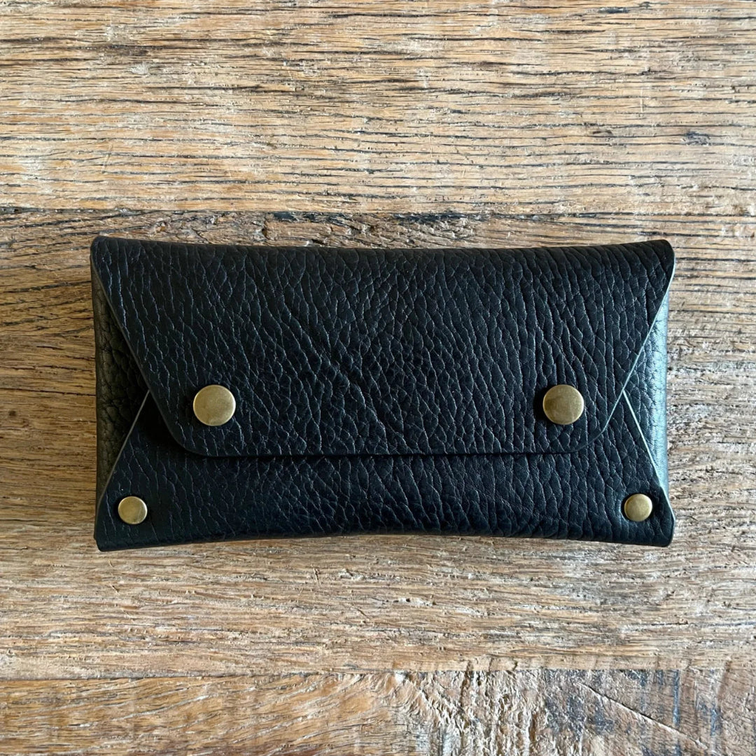 Black leather wallet with gold studs on a wooden surface